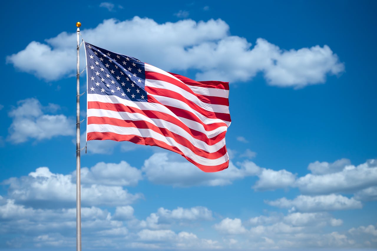 USA flag flying on flagpole against blue sky on patriotic holiday