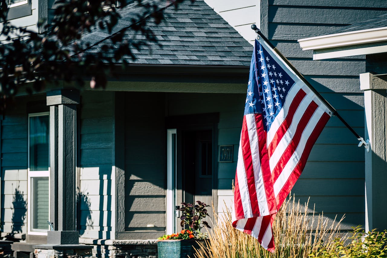 American flag mounted on a front porch of a suburban home with landscaped yard