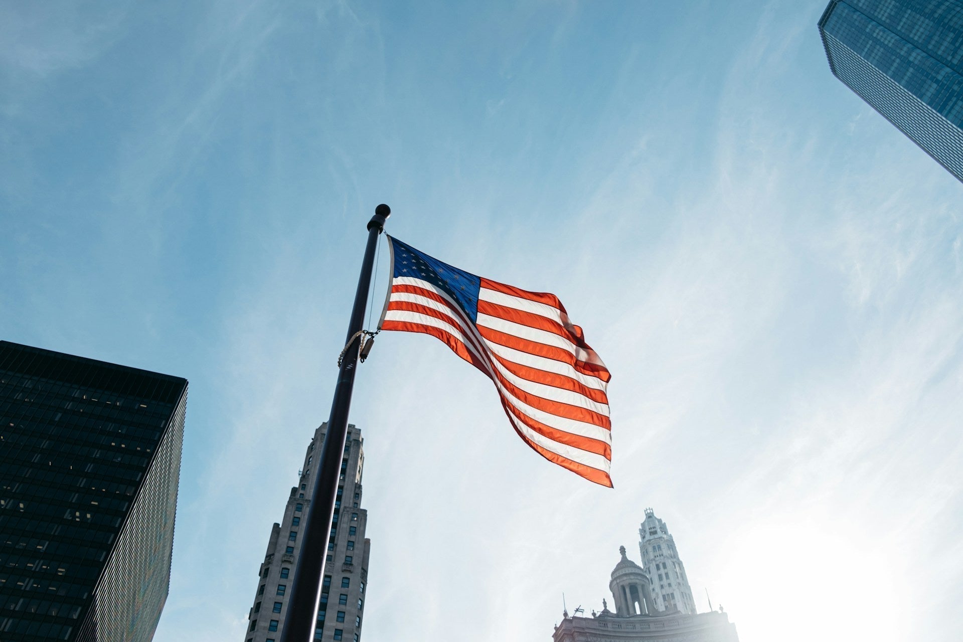 American flag flying on tall pole with city skyscrapers in background for 9/11 remembrance