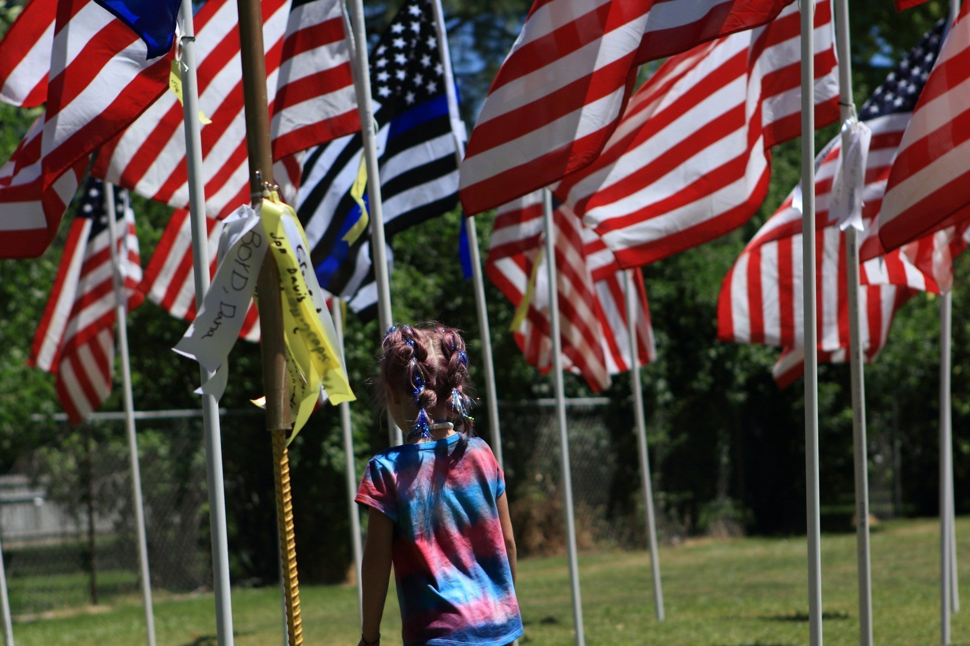 American flag flying on flagpole in front yard with children playing nearby