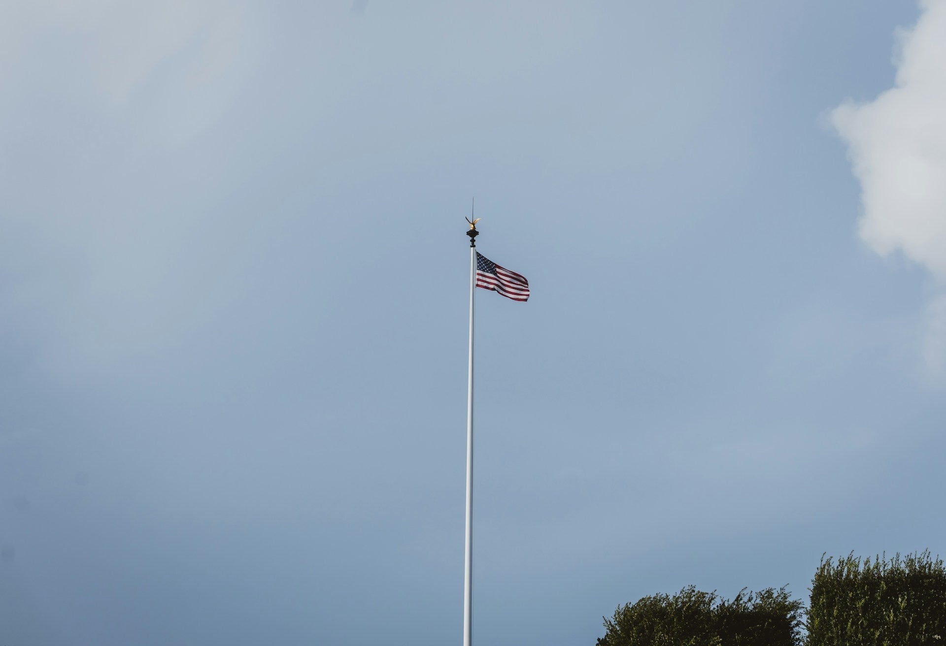 American flag flying on a smart flagpole with automatic raising system outside a modern USA home