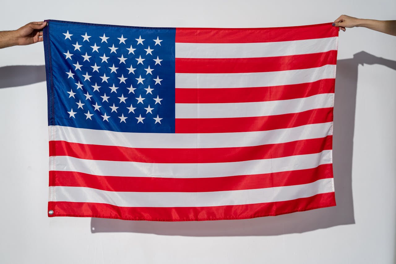 full view of USA flag held out horizontally indoors against white background